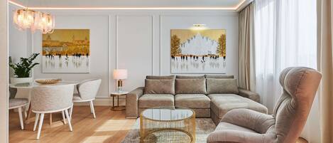 Un salon moderne comprenant un canapé, un fauteuil et une table basse, un coin repas avec des chaises et une table, ainsi que des œuvres d’art accrochées aux murs.