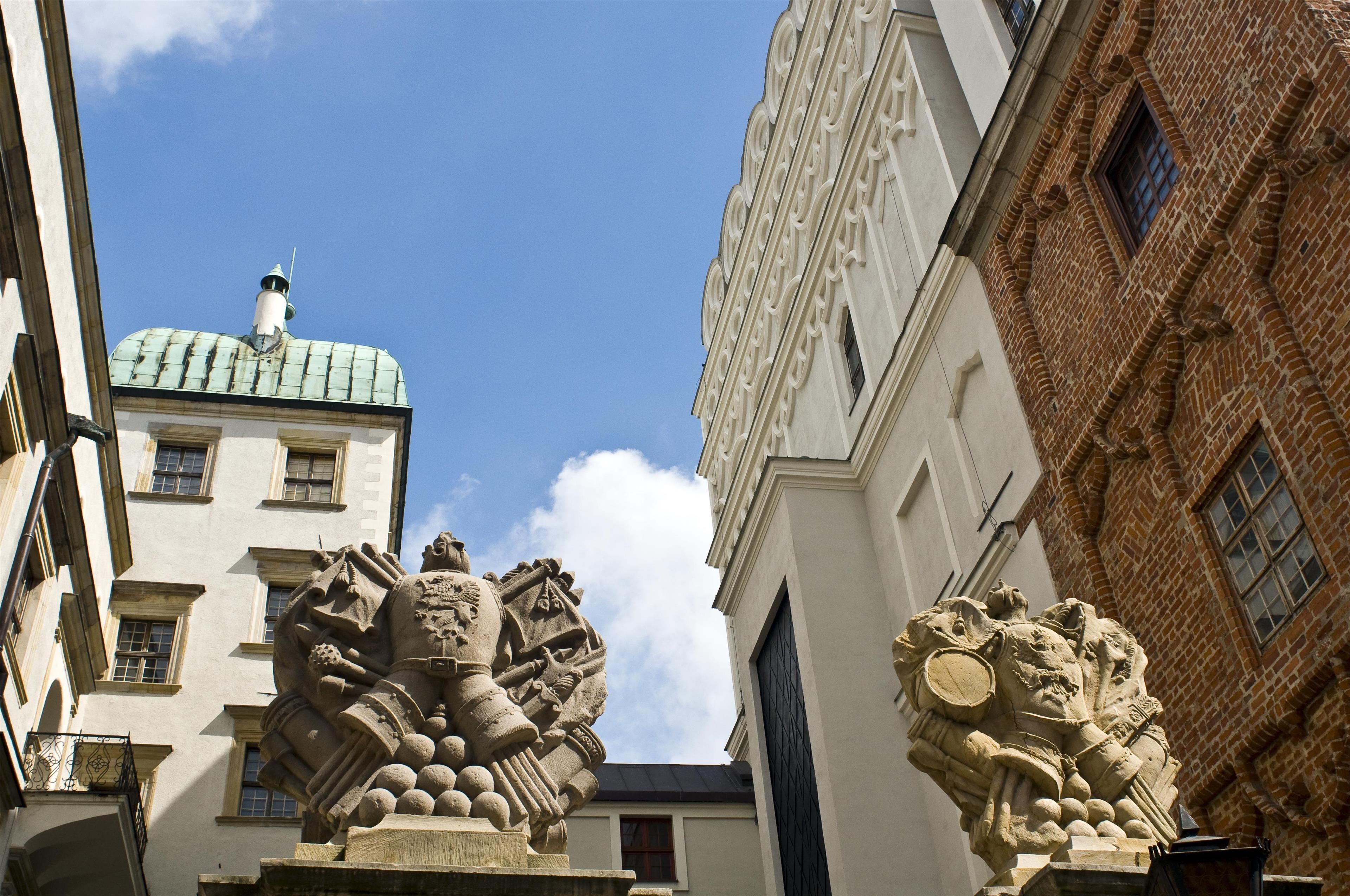 A building with a prominent stone lion statue at the entrance, a tiled roof, and a brick facade.