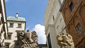 A building with a prominent stone lion statue at the entrance, a tiled roof, and a brick facade.