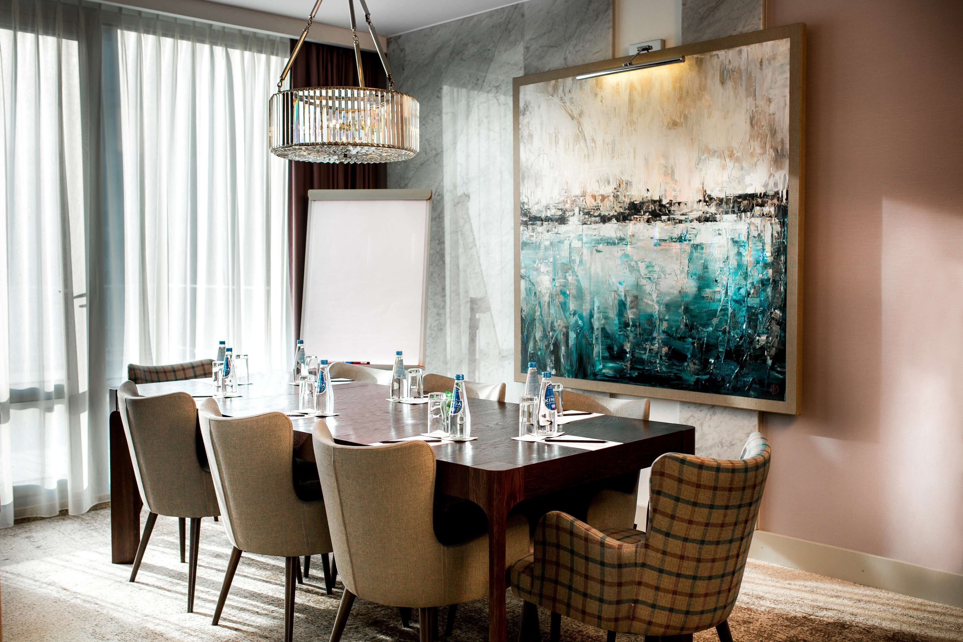 Un'area pranzo con un tavolo grande, sedie, un lampadario e un quadro appeso al muro.