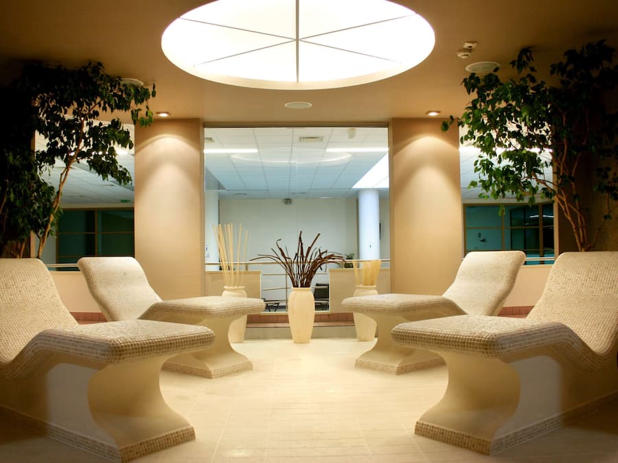 A lobby with two lounge chairs, a central vase, and a large circular light fixture.