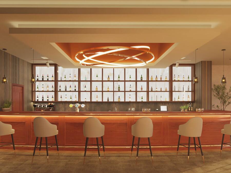 Een bar met een houten toonbank, verschillende barkrukken en een wand vol wijnflessen.