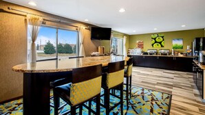 Una cocina moderna con barra, ventanas amplias y televisor de pantalla plana.