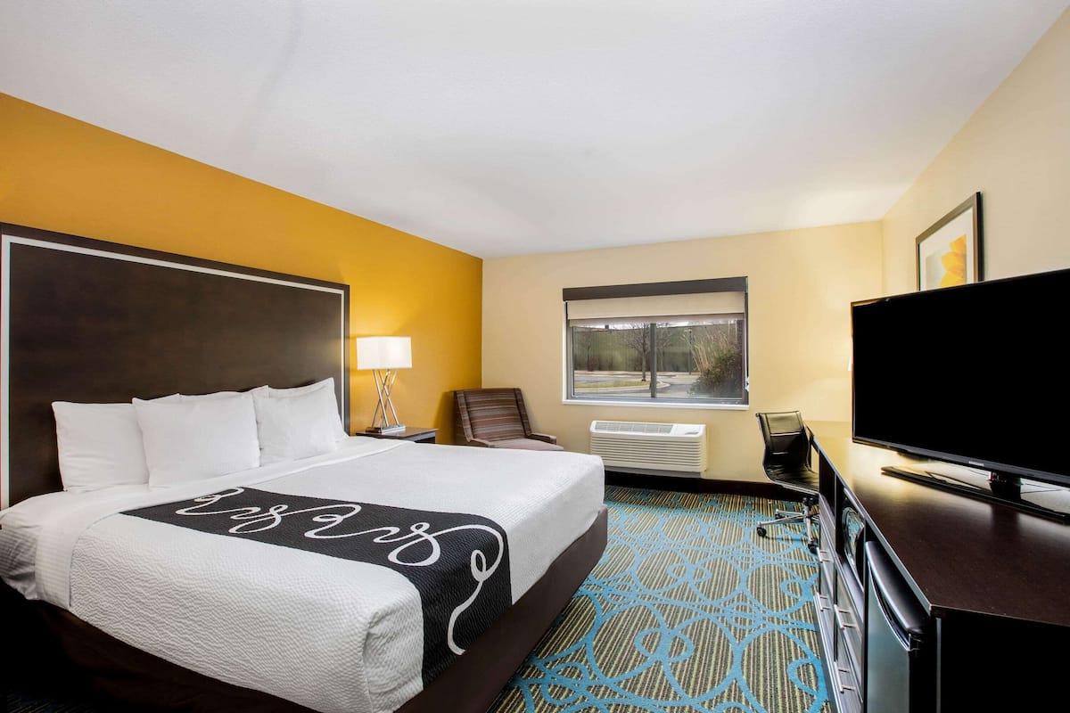 Ein Hotelzimmer mit einem großen Bett, einem Flachbildfernseher, einem Schreibtisch und einem Fenster mit Blick.