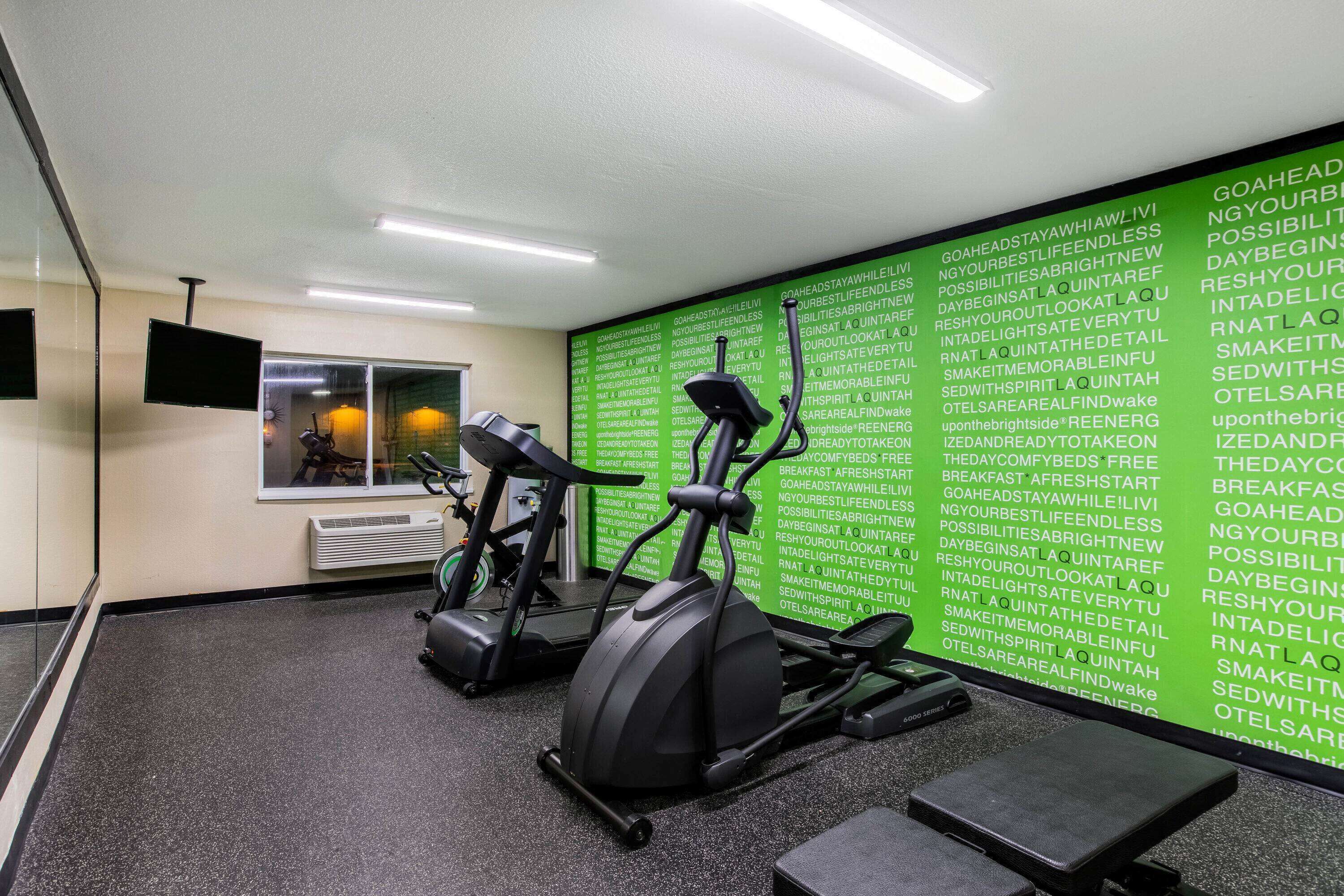 Un gimnasio con dos bicicletas estáticas y una pared con citas motivacionales.
