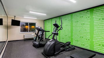 A gym with two stationary bikes and a wall with motivational quotes.
