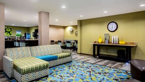 Un hall de hotel con un sofá estampado, un reloj y una recepción con adornos.
