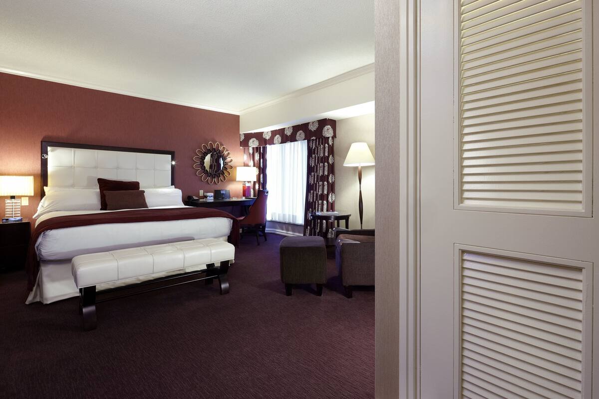 A hotel room with a large bed, a desk, a chair, and a small table.