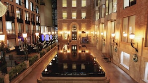 A hotel lobby with a central reflective pool, multiple dining areas, and a grand entrance with a wreath.