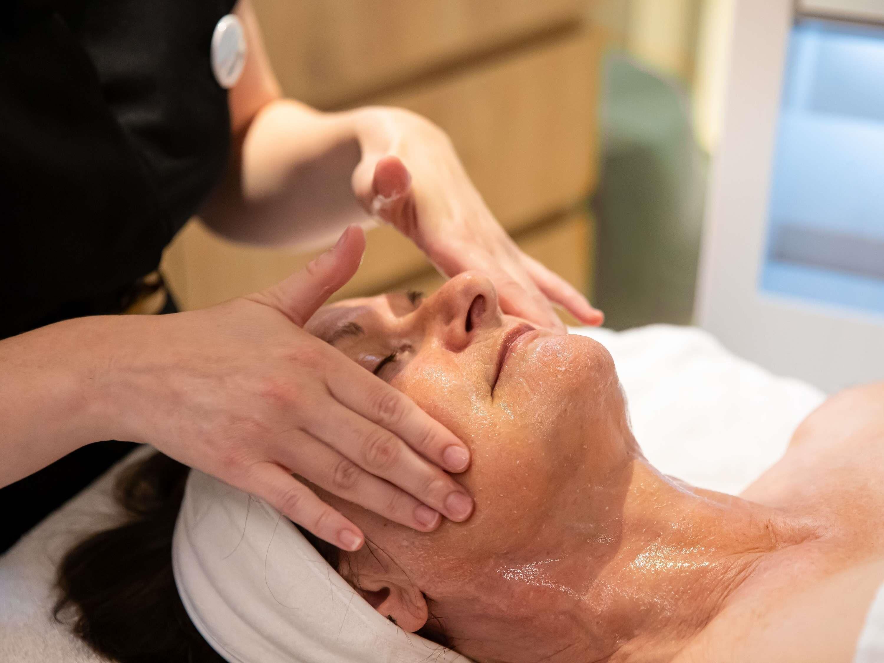 A person receiving a facial treatment with a white towel and a device on their head.