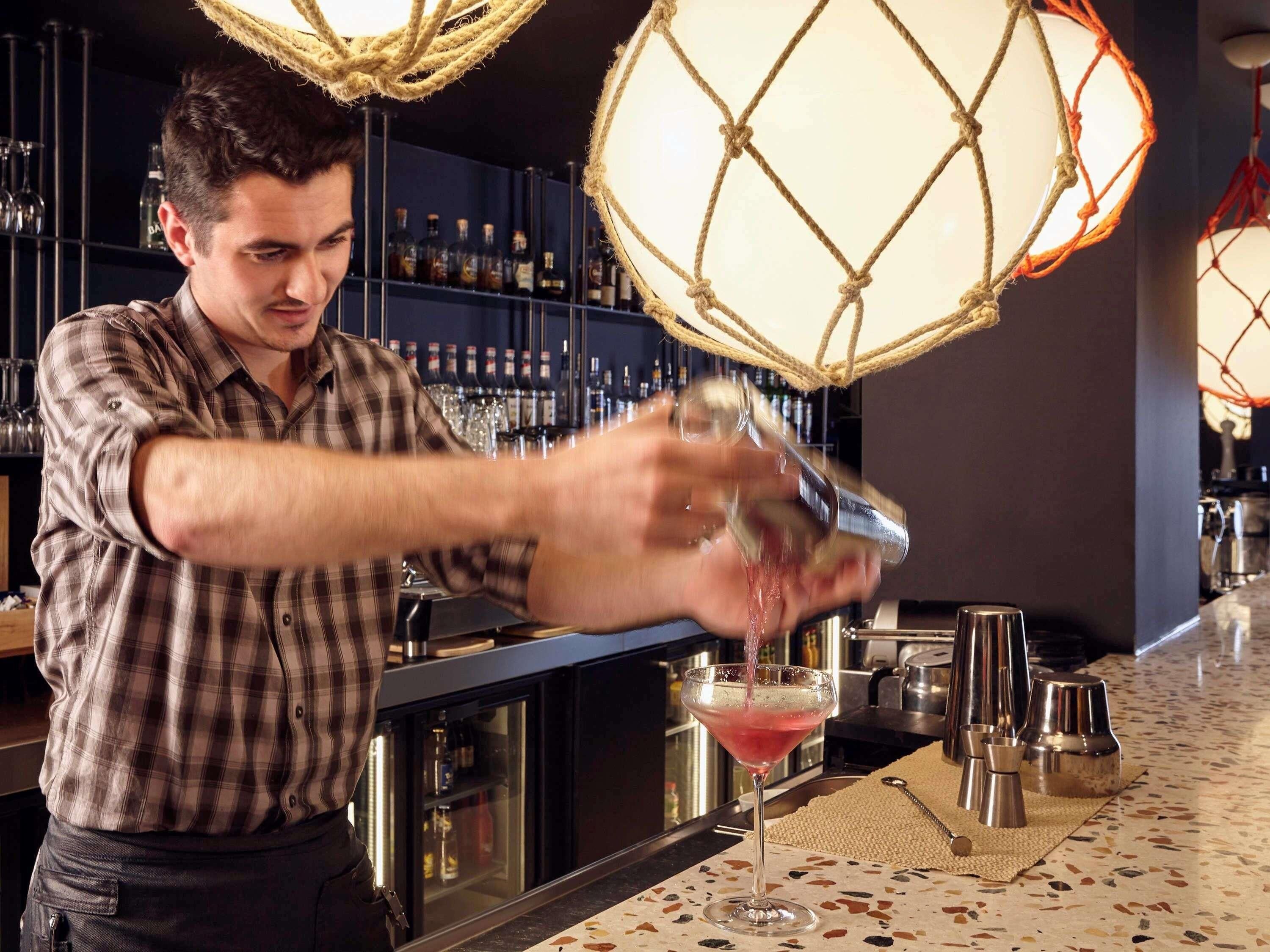 A bartender pouring a drink into a martini glass.