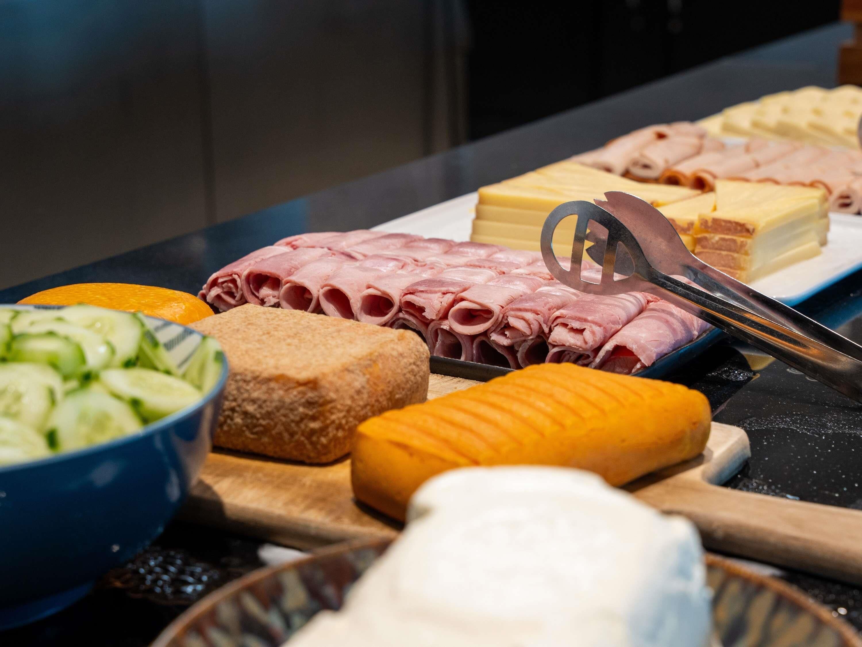 A buffet table with various food items including sliced meats, cheeses, and vegetables.