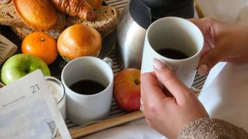 Un plateau contenant des croissants, du pain, des oranges et une pomme, accompagné de deux tasses de café.