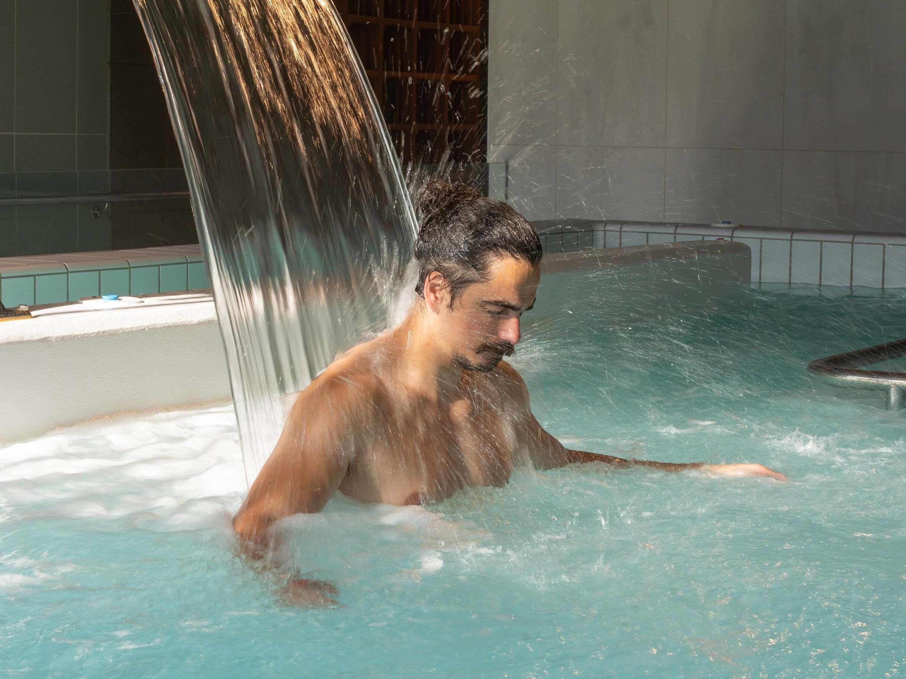 A person in a hot tub with a waterfall feature.