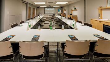 A conference room with a long table, chairs, water bottles, and a projector screen displaying 'Thalassa SEA&SPA LE TOUQUET'.