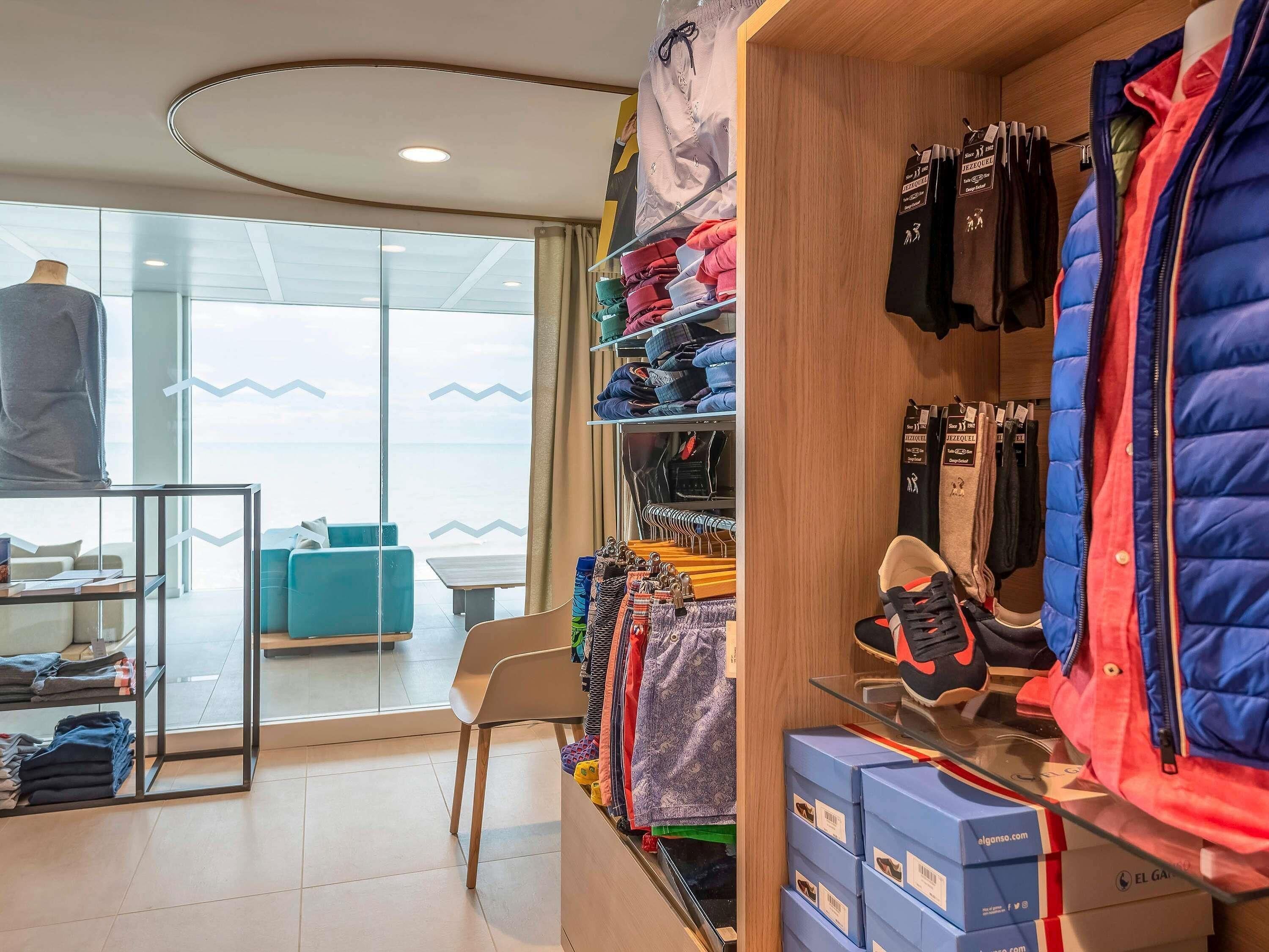 A clothing store with racks of jackets and pants, a mannequin, and a chair.