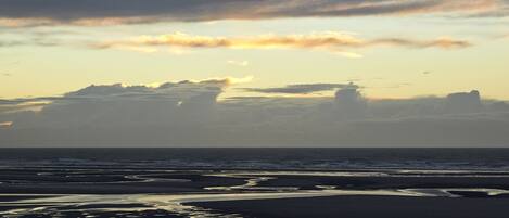A beach with a calm sea and a cloudy sky.