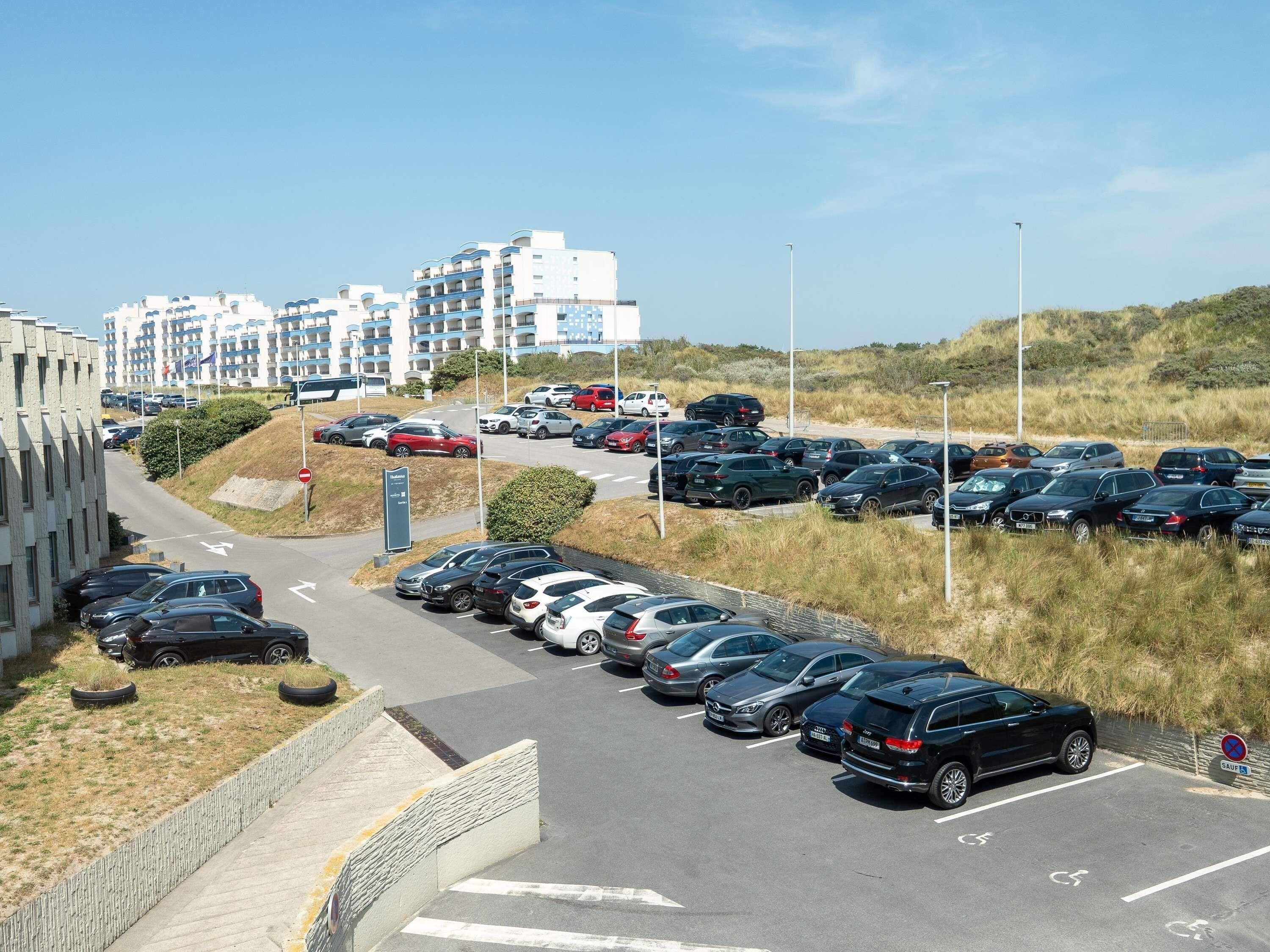 A parking lot with multiple cars and a building in the background.
