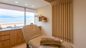 A room with a view of the beach, a massage chair, wooden slats on the wall, and a shelf with candles. - Novotel Thalassa Le Touquet Hotel (Le Touquet-Paris-Plage)