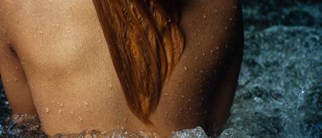 Una persona de cabello largo sentada en una bañera llena de agua.