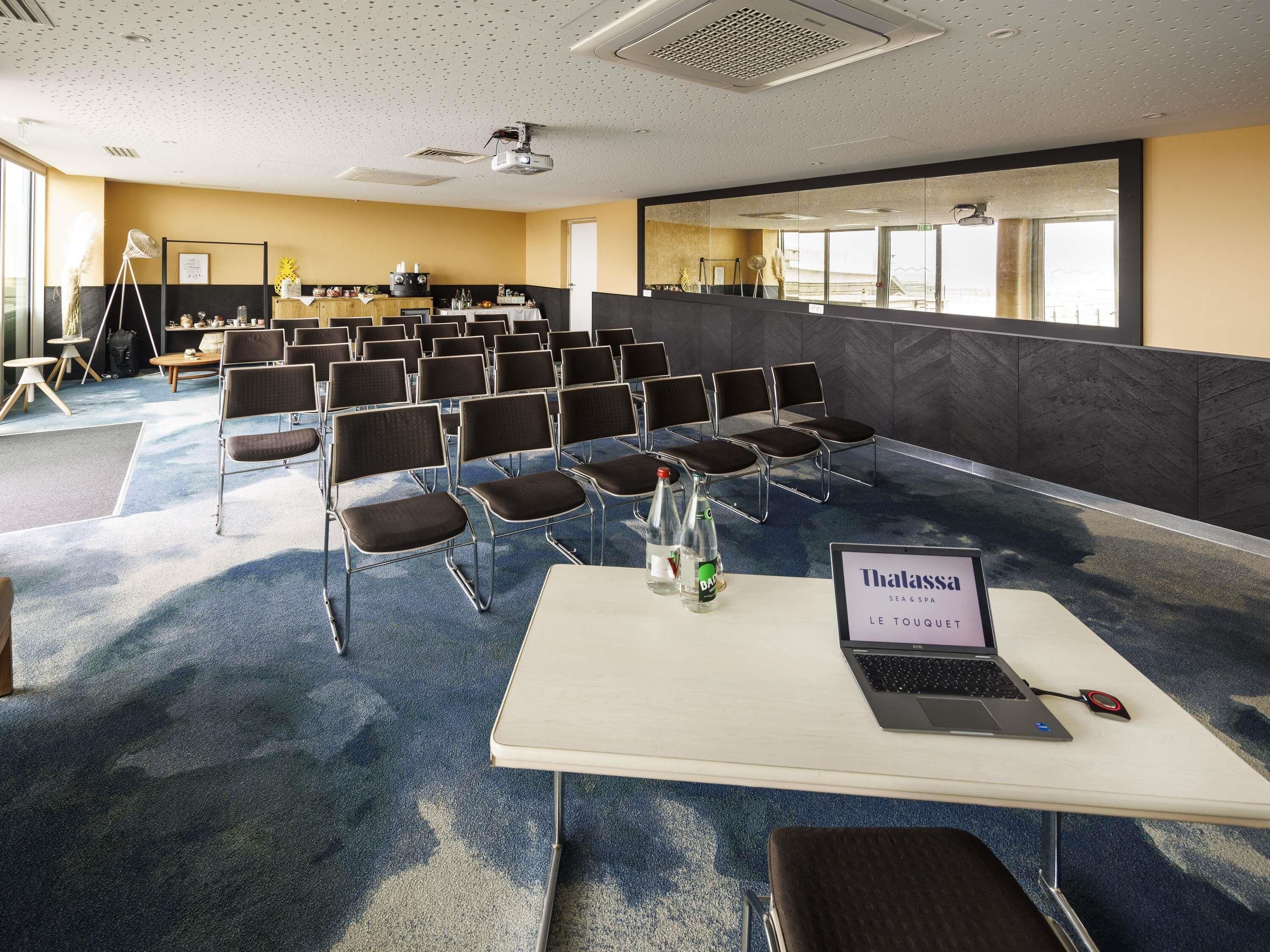 A conference room with rows of chairs, a projector, and a laptop on a table.