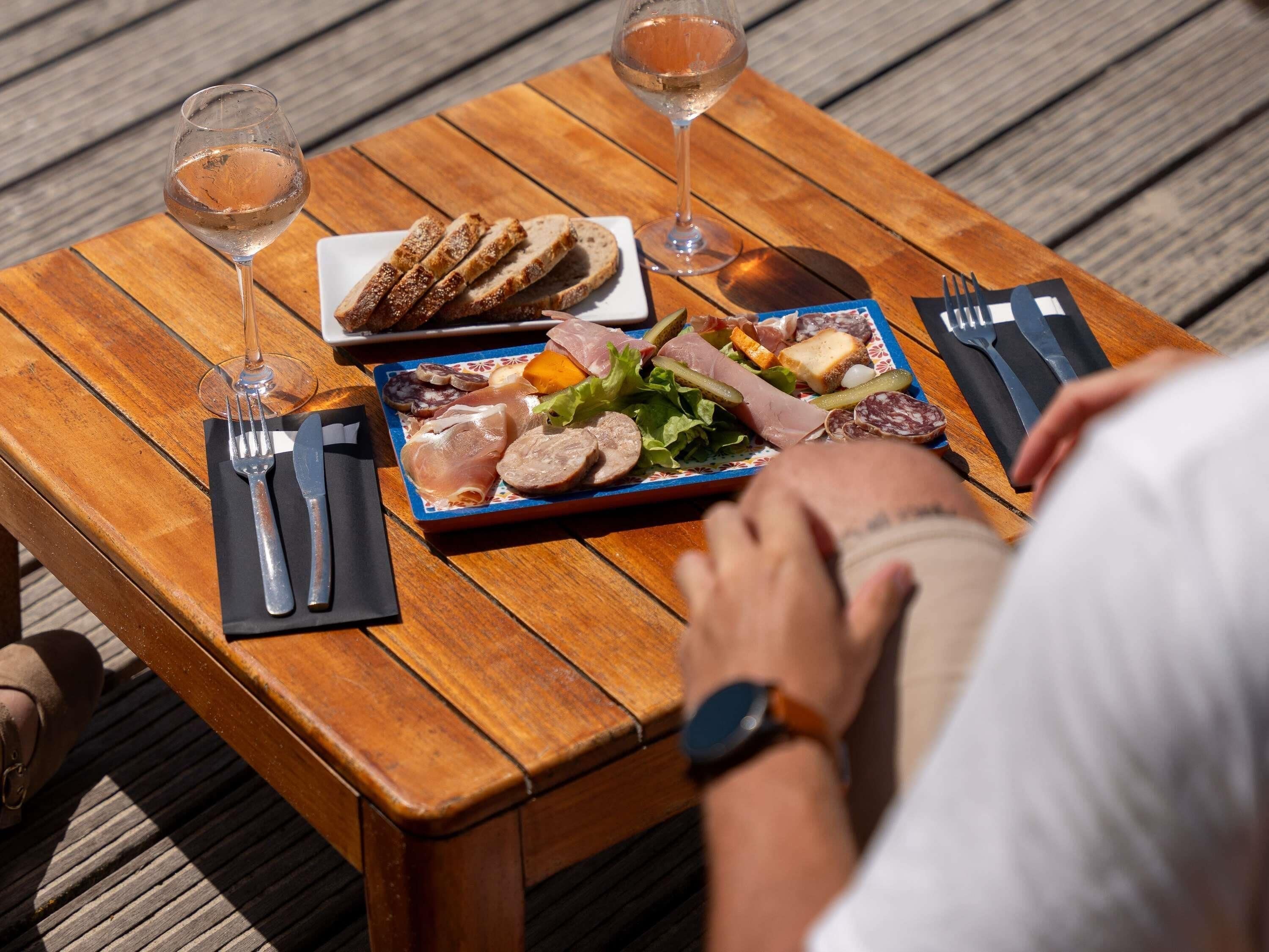 A wooden table with a meal, wine glasses, and cutlery.