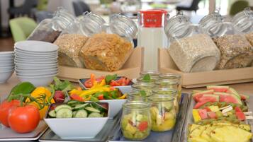 Ein reichhaltiges Buffet mit verschiedenen Speisen, darunter Salate, Früchte und Getreide.