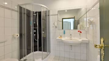 Ein modernes Badezimmer mit einer gläsernen Duschkabine, einem weißen Waschbecken und einem Spiegel.