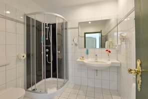 A modern bathroom with a glass-enclosed shower, a white sink, and a mirror. - Hotel Stadt Hameln (Hamelin)