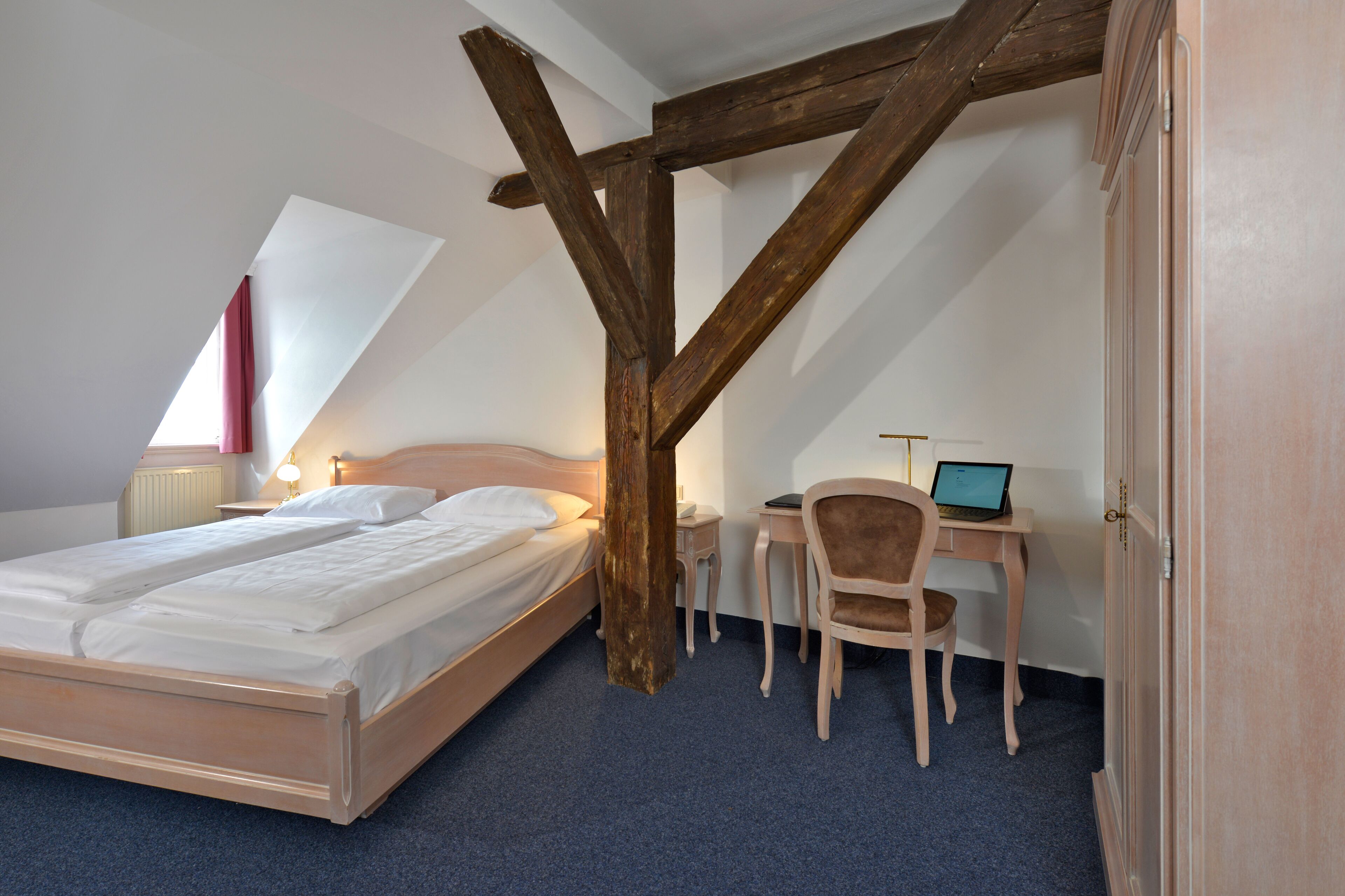 A bedroom with a bed, a desk, and a chair.