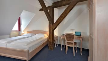 A bedroom with a bed, a desk, and a chair.