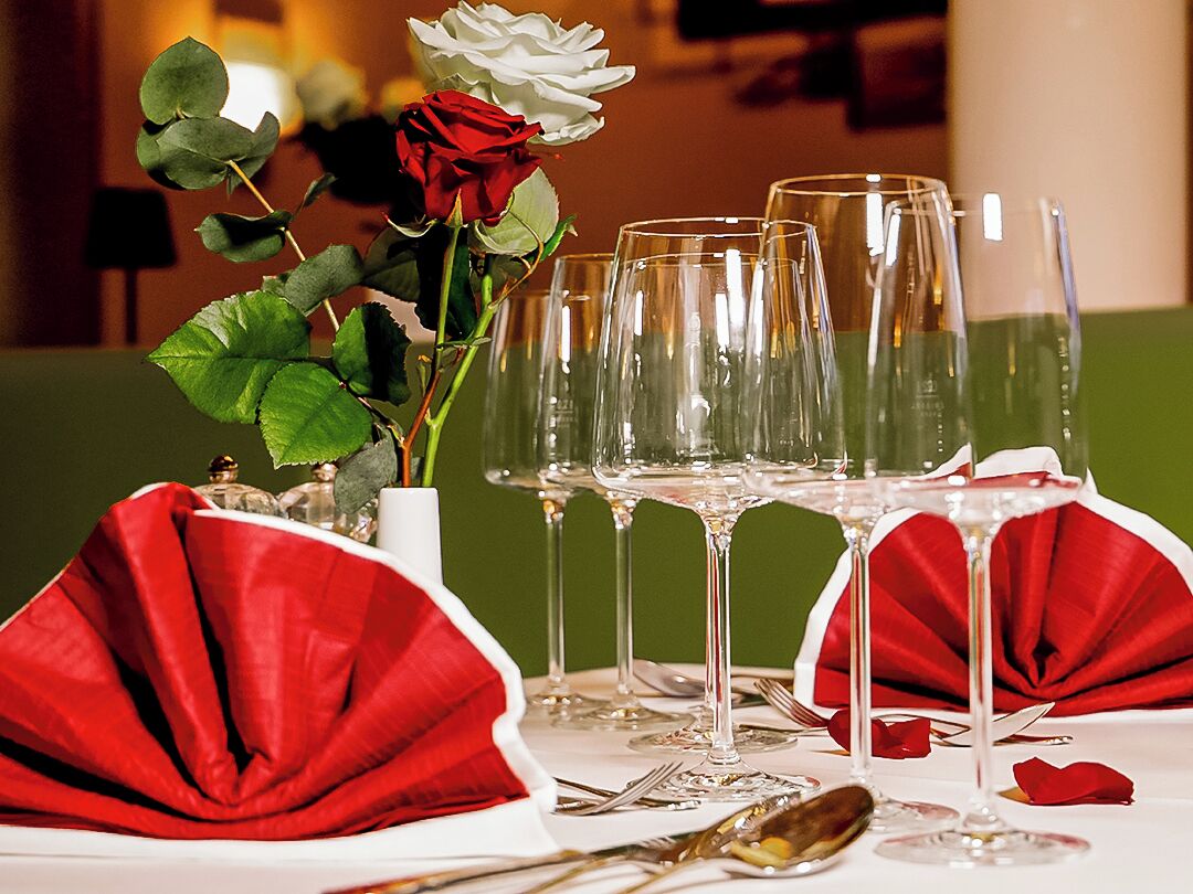 Mesa dispuesta para una cena formal, con varias copas de vino y un jarrón con flores.
