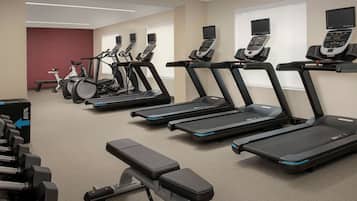 A gym with multiple treadmills, stationary bikes, and dumbbells.
