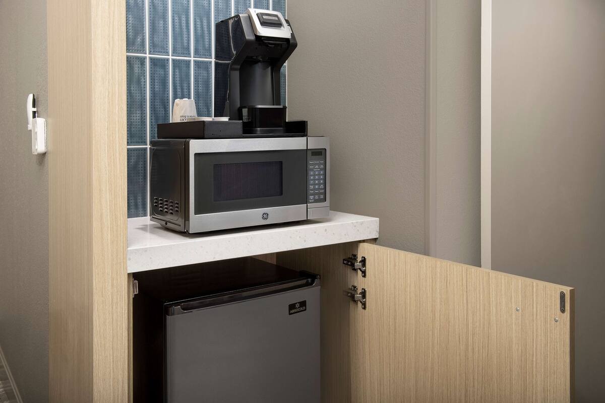 A compact kitchen with a microwave, coffee machine, and a small refrigerator.