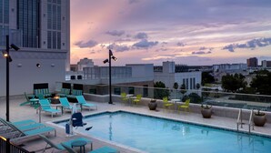 A rooftop pool with lounge chairs and tables, surrounded by city buildings. - Hilton Garden Inn Orlando Downtown (Orlando)