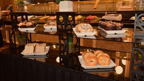 A buffet with various food items including bread, pastries, and a variety of dishes.