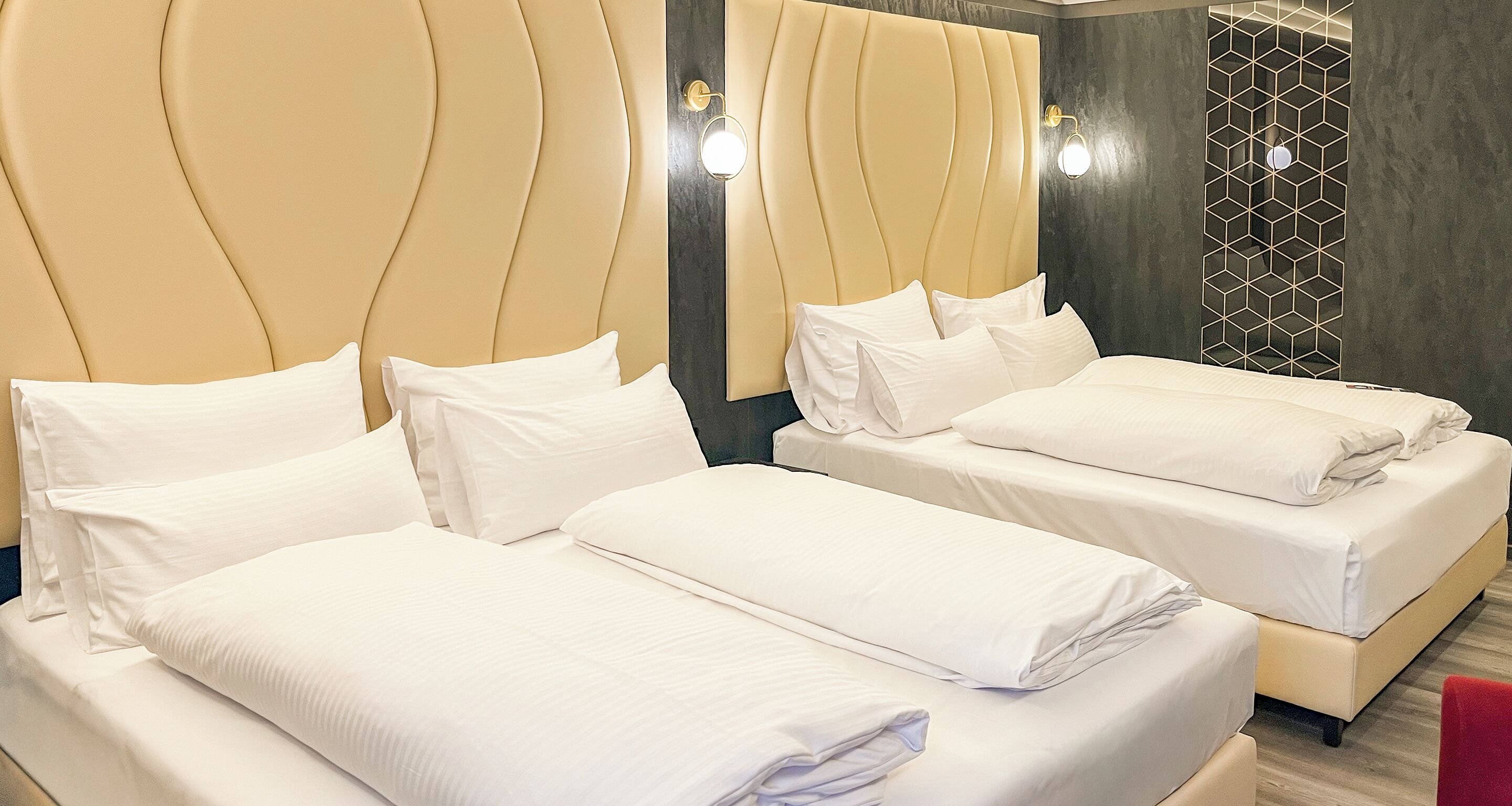 Habitación de hotel con dos camas, cada una con ropa blanca y cabeceros.