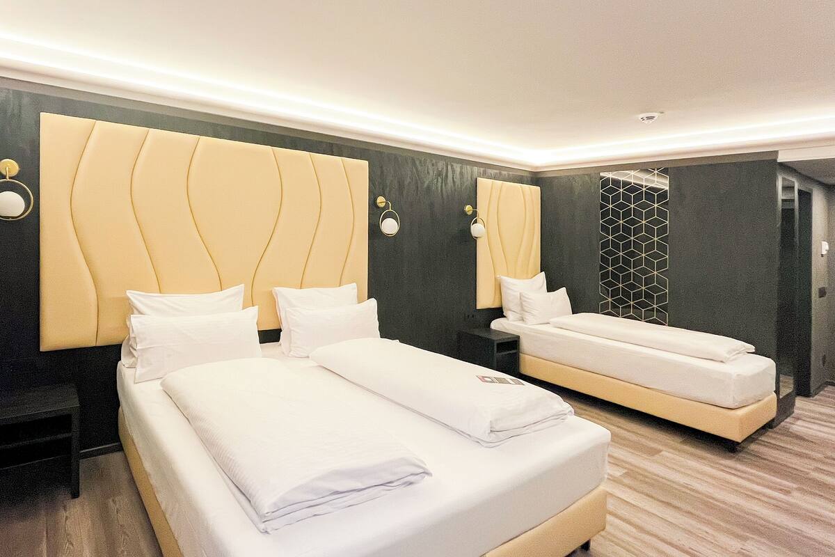 Ein Hotelzimmer mit zwei Betten, dunklen Wänden und modernem Design.