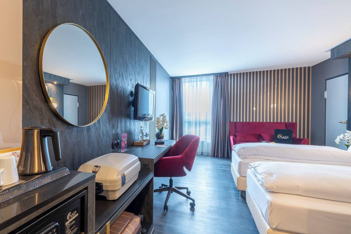 Ein Hotelzimmer mit Schreibtisch, Stuhl, Bett, Fernseher und einem großen Spiegel.