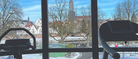 A room with a large window overlooking a cityscape, including a church spire and residential buildings.
