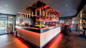 A modern bar area with a central counter, pendant lighting, and a red-lit ceiling.