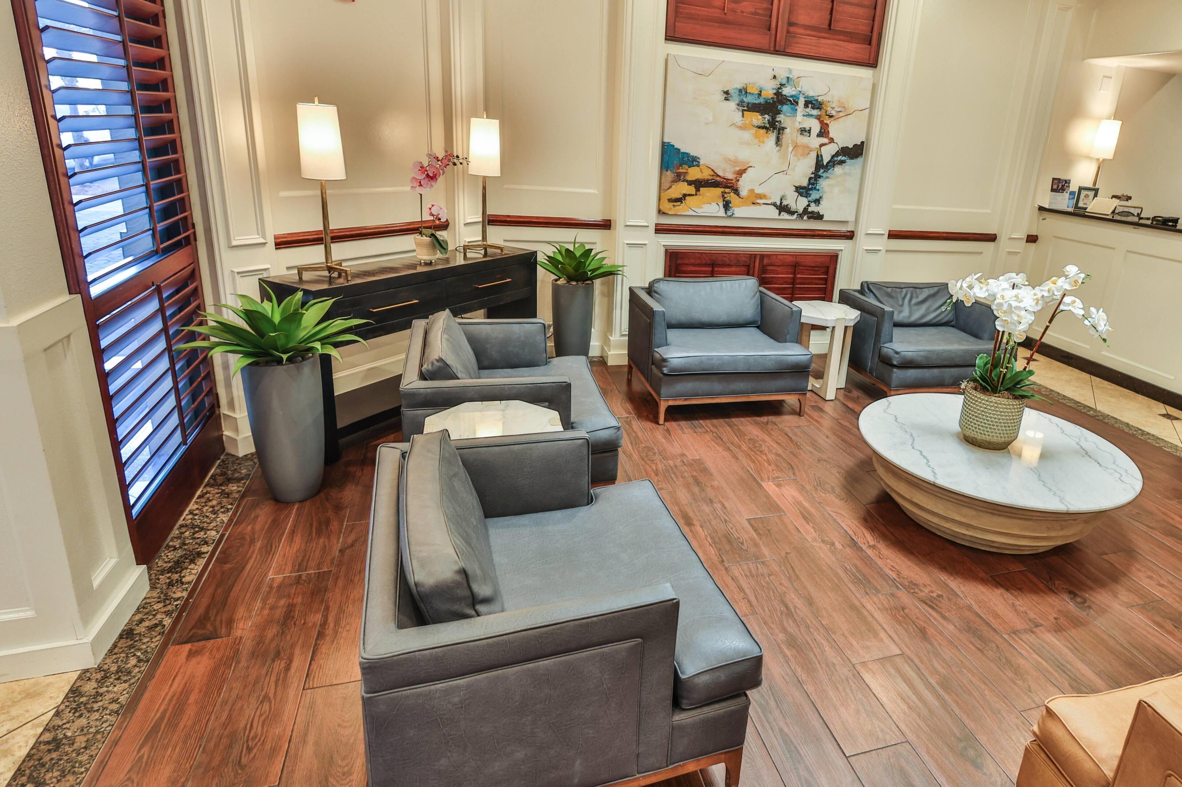 A modern lobby with a sofa set, a round coffee table, and a painting on the wall.