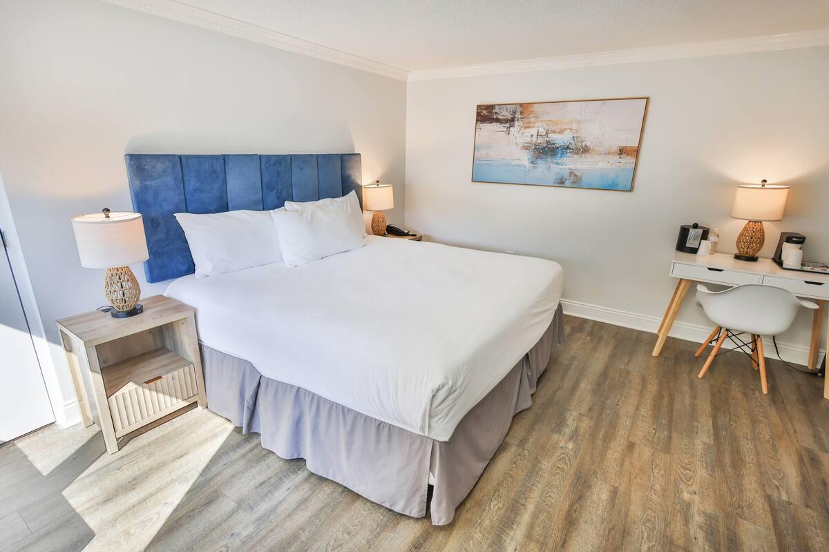 Ein ordentlich eingerichtetes Schlafzimmer mit einem großen Bett, Nachttischen, einem Schreibtisch und einem Sessel.