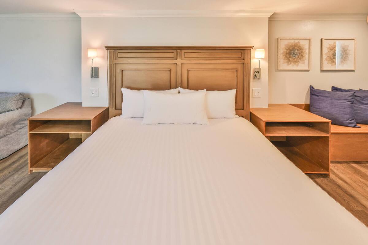Ein Hotelzimmer mit einem großen Bett, einem Holz-Kopfteil, Nachttischen und Wandlampen.
