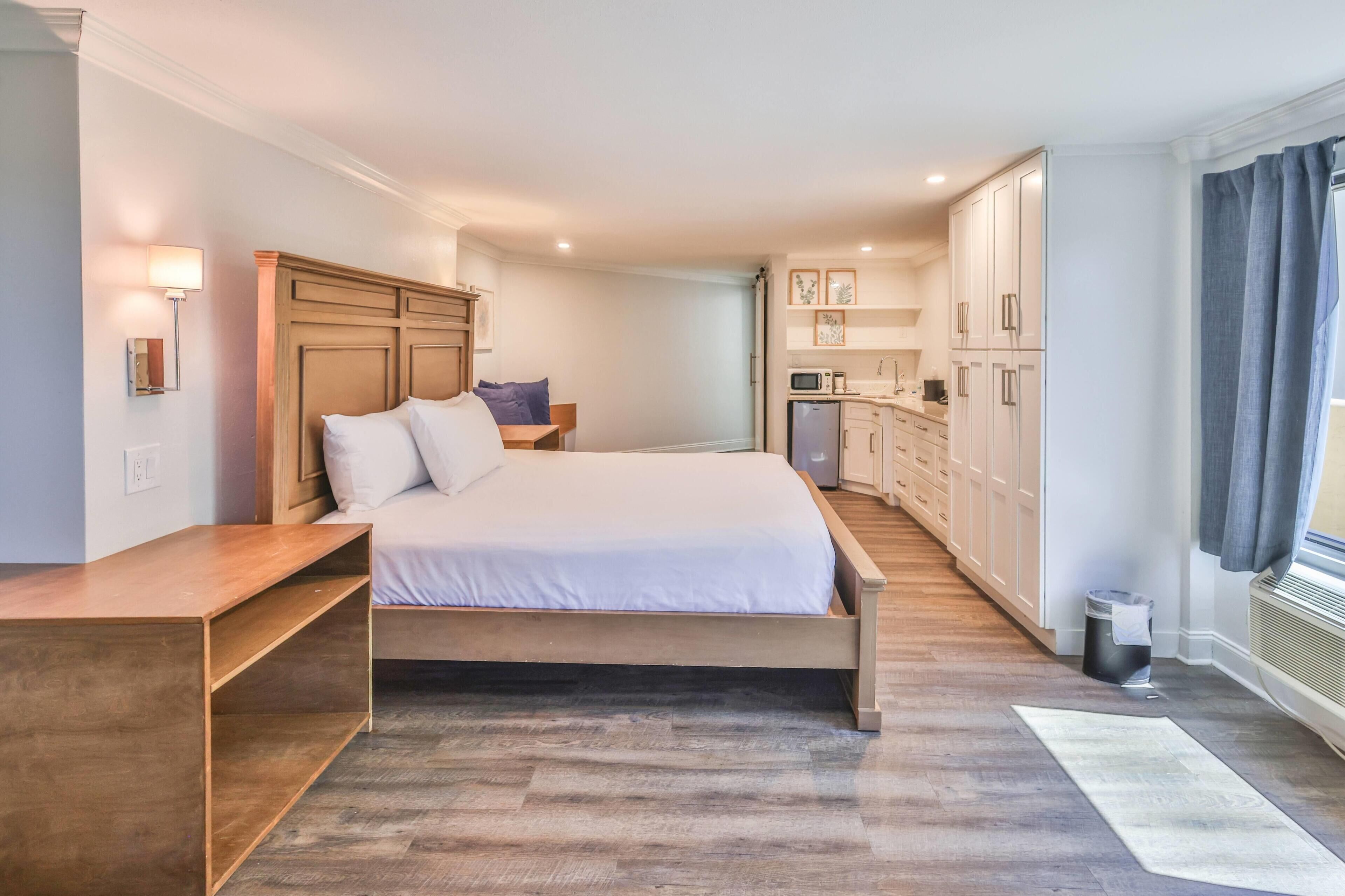Een slaapkamer met een bed, houten hoofdbord, nachtkastje en een klein bureau.