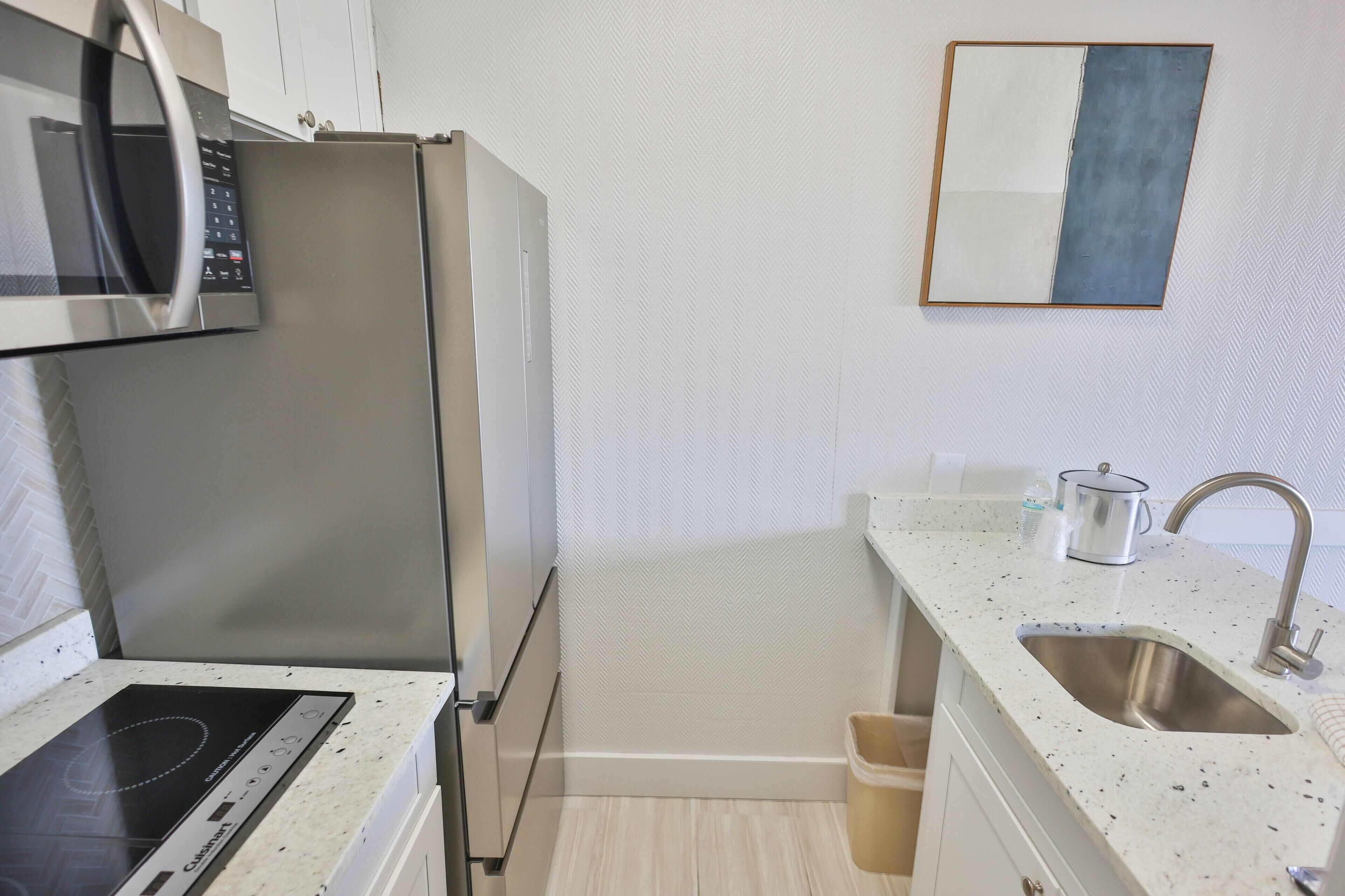 A compact kitchen with a microwave, refrigerator, stove, sink, and a small countertop area.