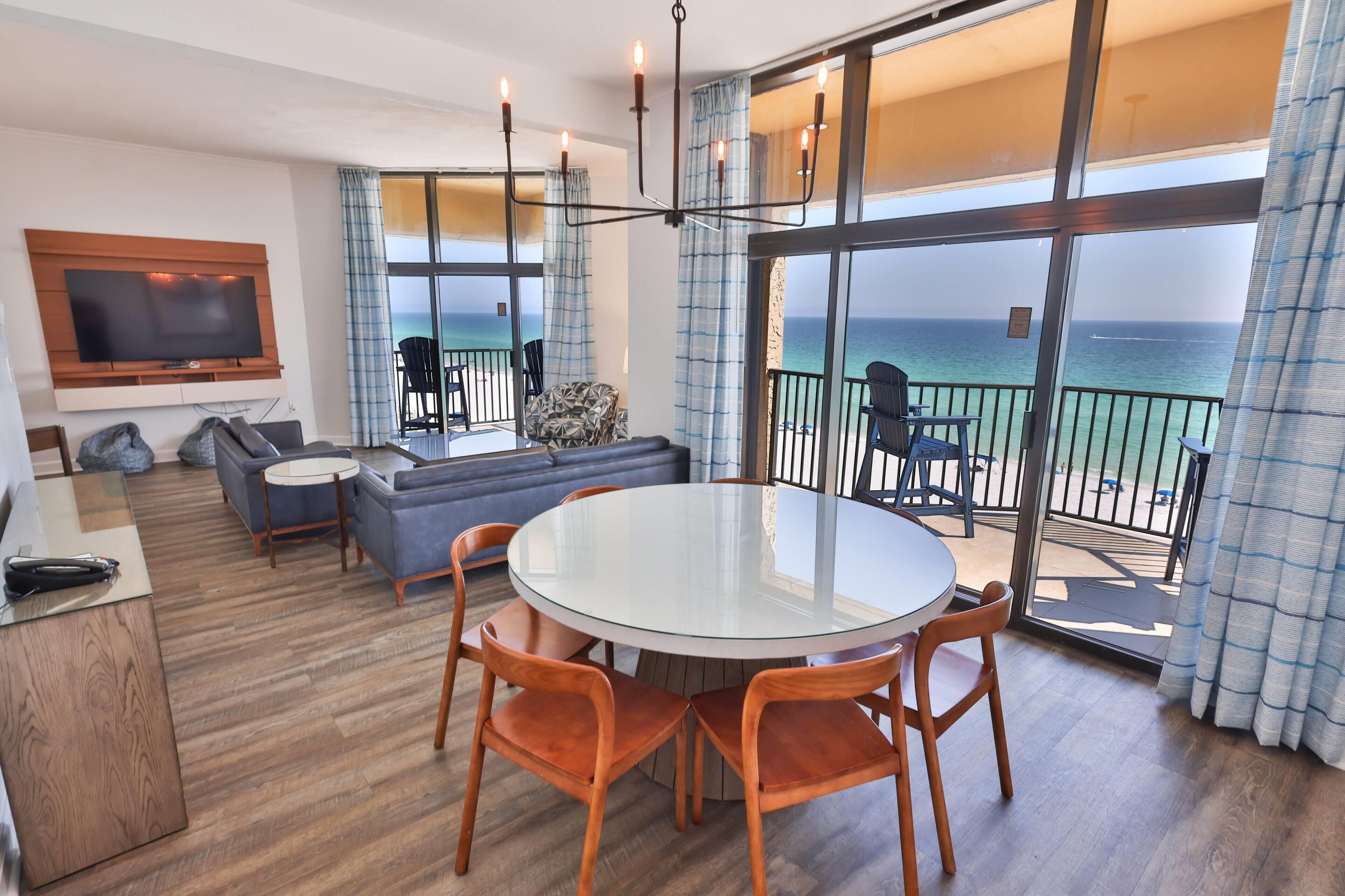 A modern living room with a glass table, sofas, and a TV.