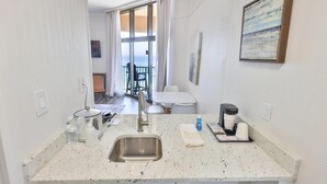 A kitchen with a sink, coffee maker, and a view of a balcony.