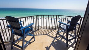 A balcony with two chairs facing a beach.