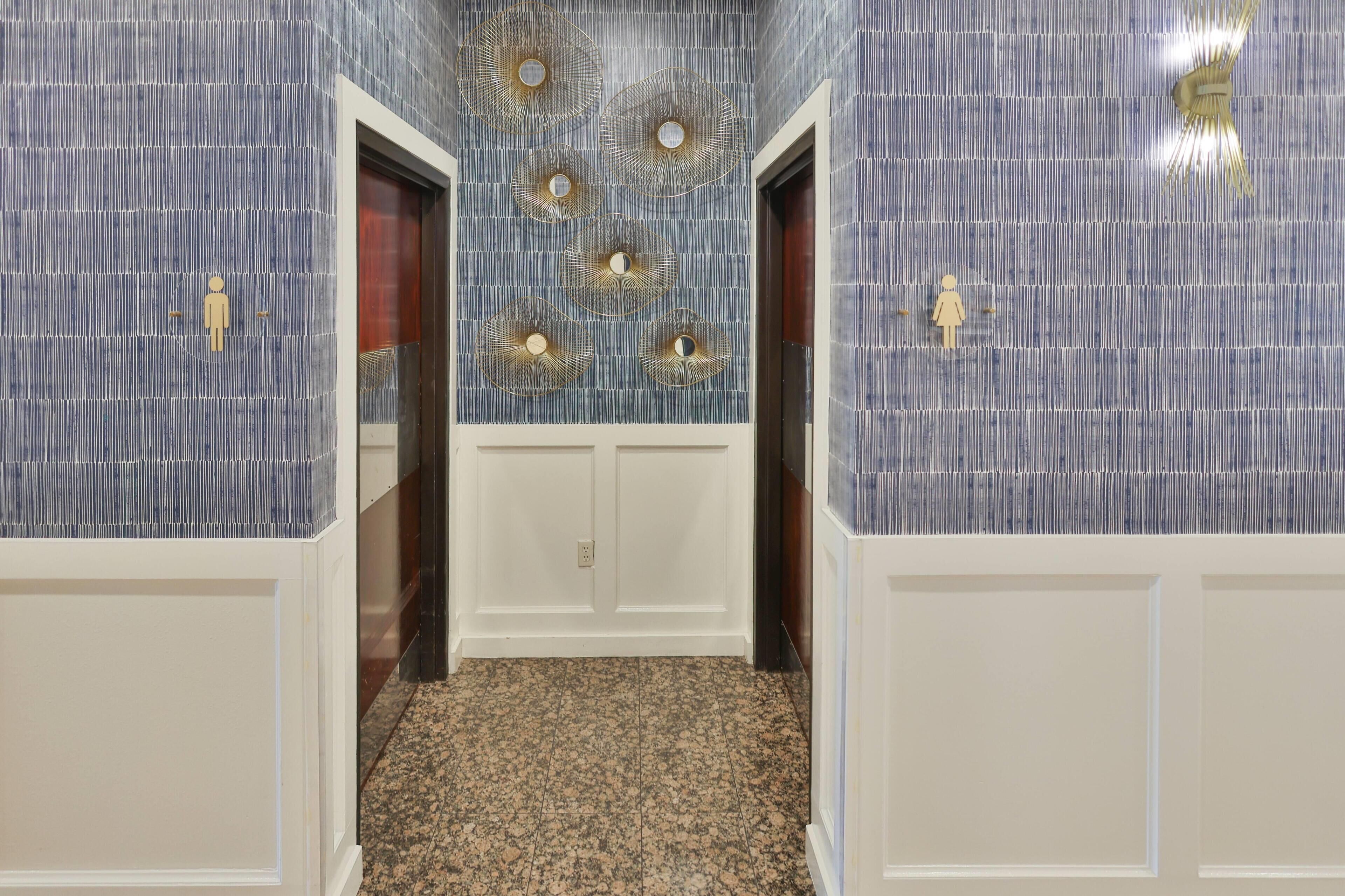 A hallway with patterned walls, a white door, and a carpeted floor.
